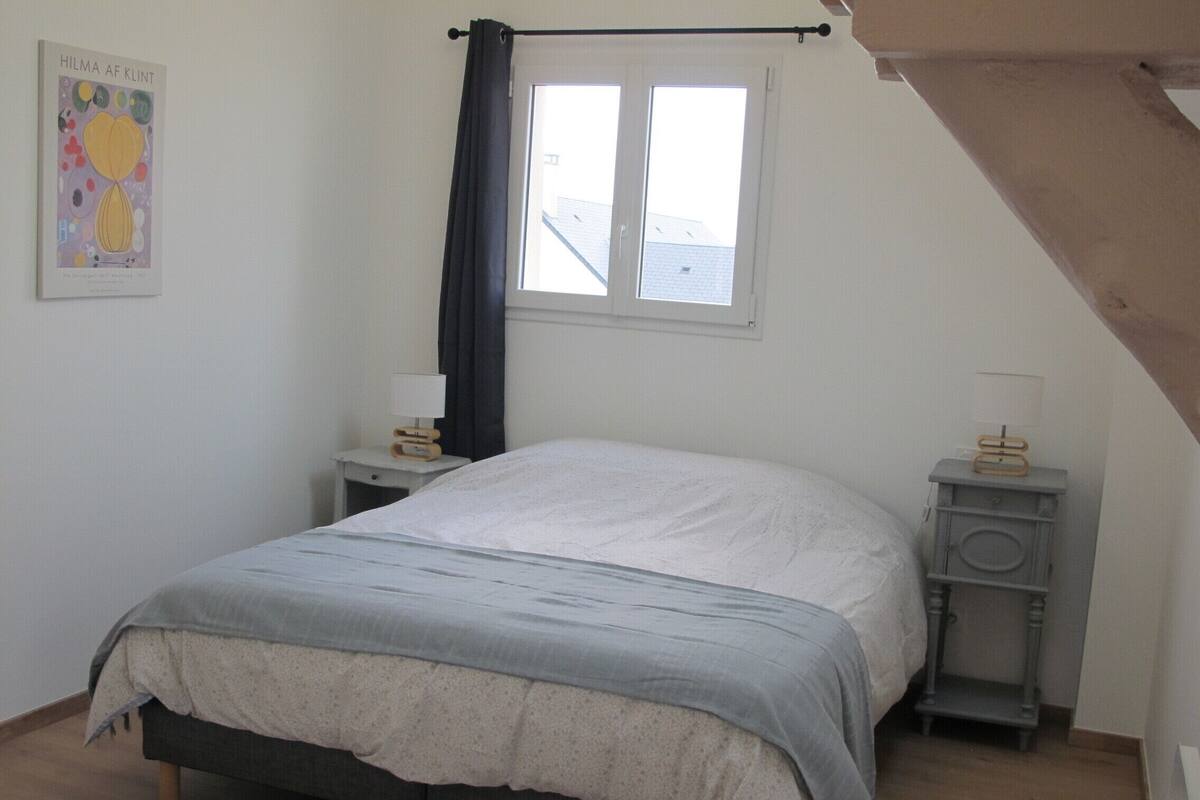 A bedroom with a bed, a nightstand, a dresser, a window with curtains, and a poster on the wall.