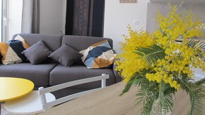 A modern living room with a grey sofa, a small round table, and a yellow table. - Rose Garden Bayeux (Bayeux)