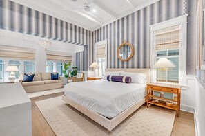 A modern bedroom with a large bed, a sofa, and a wooden nightstand.