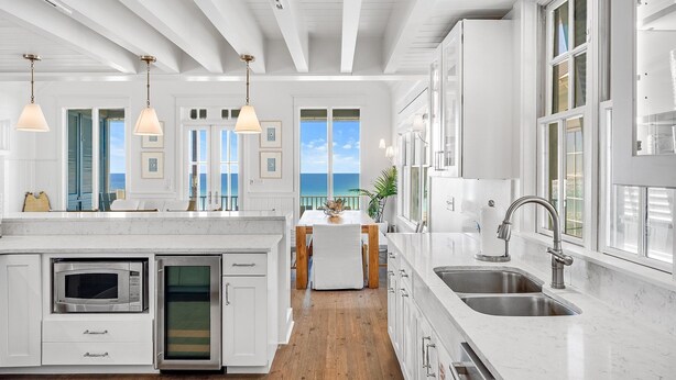 Una cocina moderna con armarios blancos, microondas integrado y un fregadero.
