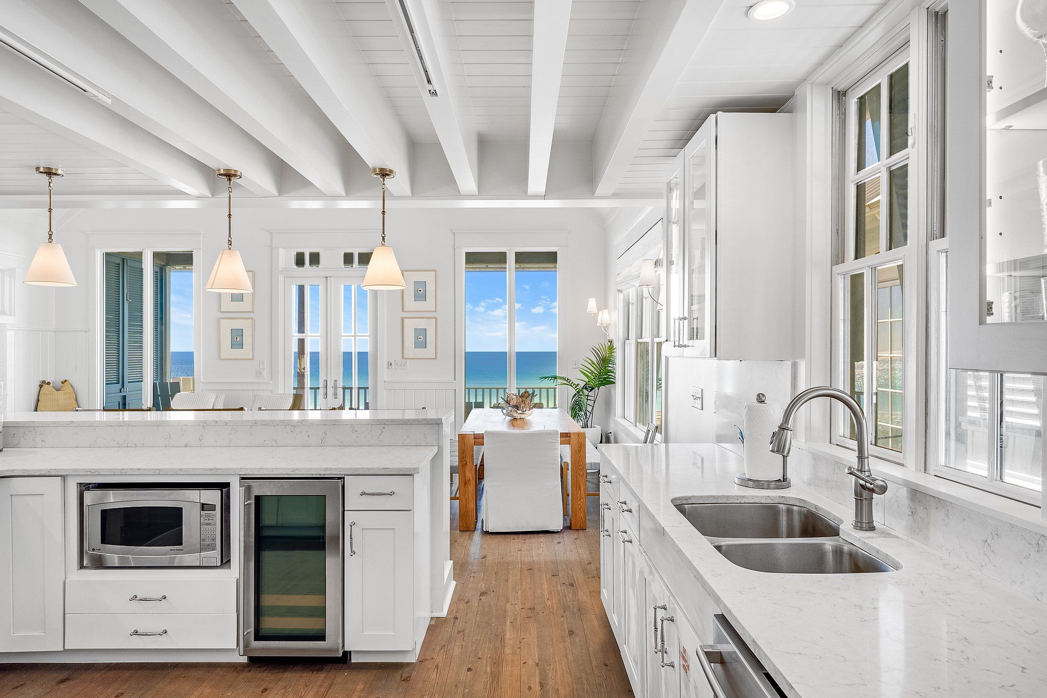A modern kitchen with white cabinetry, a built-in microwave, and a sink.