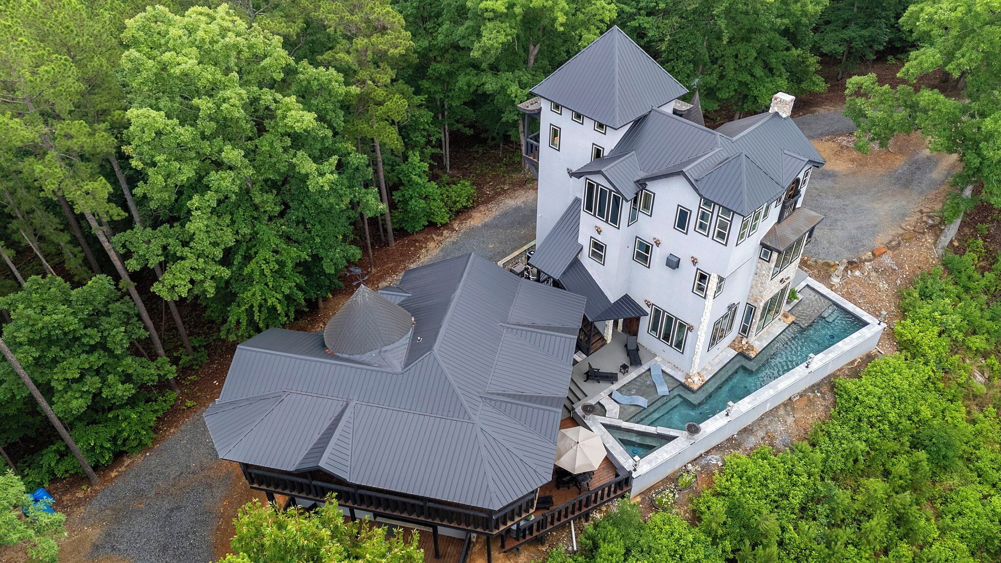 A multi-story house with a large deck and a swimming pool.