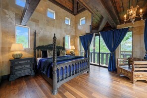 Een slaapkamer met een hemelbed, houten vloeren, stenen muren en een balkon met uitzicht.