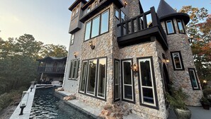 A multi-story stone building with large windows, a turret, and a water feature in front.