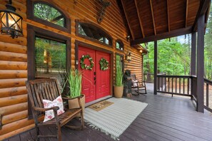 A wooden cabin with a porch, red doors, and a bench.