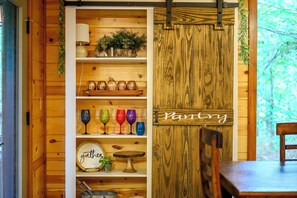 Ein Holzinterieur mit einem 'Party'-Schild, Regalen voller Glaswaren und einem Essbereich.