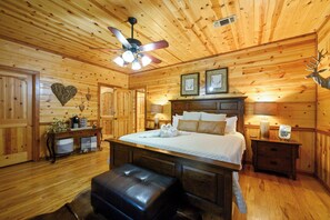 A wooden cabin interior with a bed, a bench, a table with a lamp, and a ceiling fan. - # Time Well Spent  ## Luxury Broken Bow Cabin with Hot Tub, Creek, Playground, a (Broken Bow)
