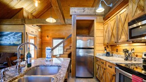 A kitchen with wooden cabinets, stainless steel appliances, and a granite countertop. - Burnt Whiskey! Beautiful Rustic Couples Cabin. (Broken Bow)