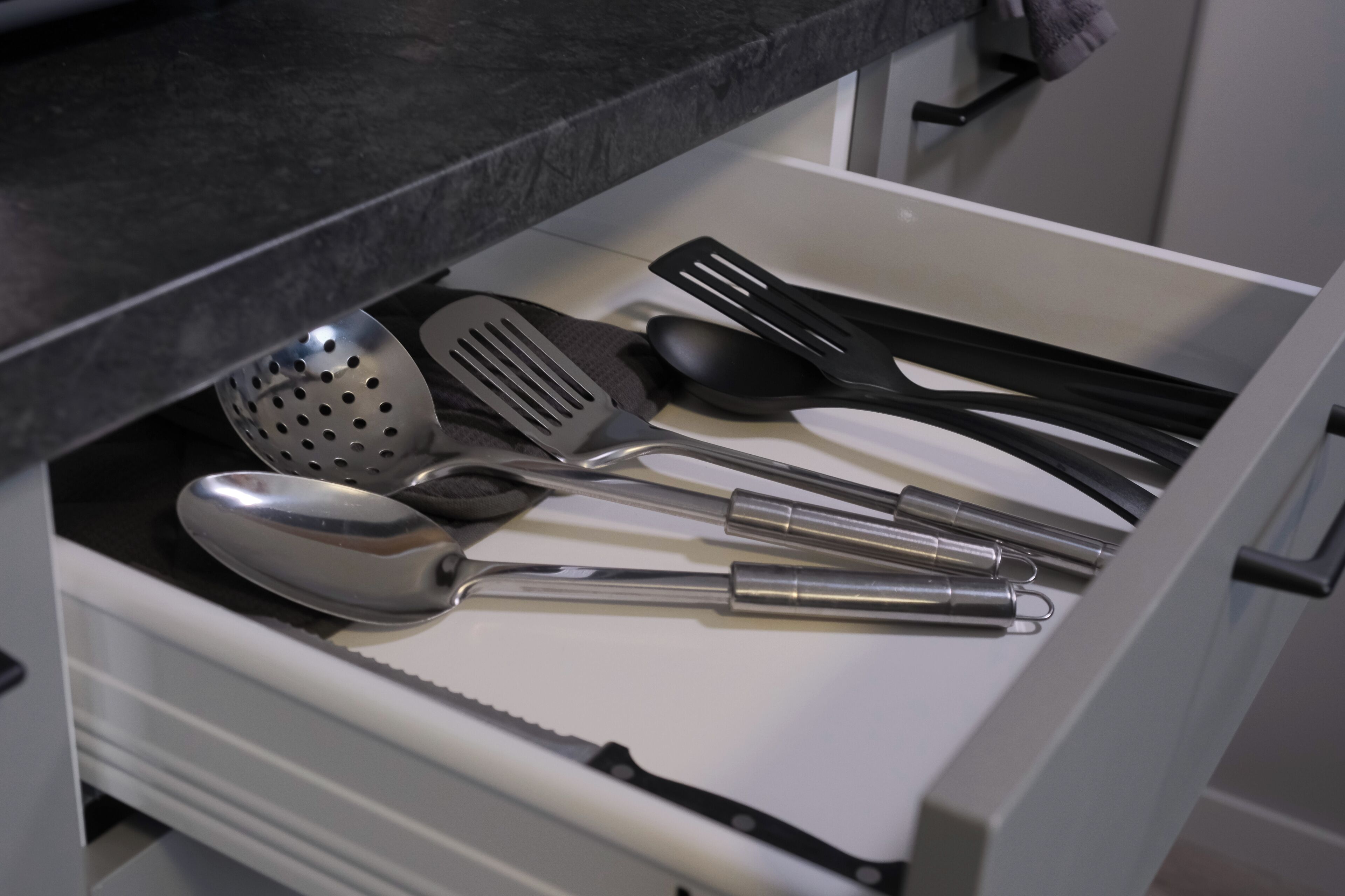 A kitchen drawer containing various utensils including a ladle, spatula, and spoon.