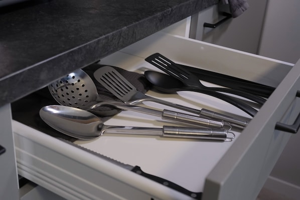 Un cajón de cocina con diversos utensilios, como una cuchara grande, una espátula y una cuchara.