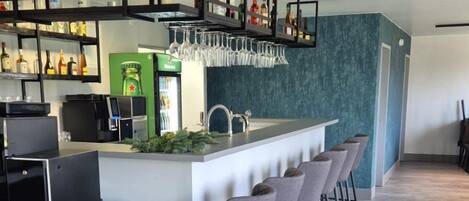 A modern kitchen with a bar area, bar stools, and a refrigerator.