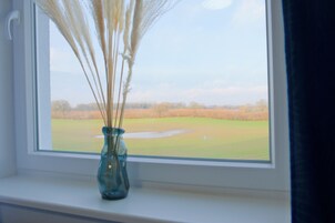 Ein Fenster mit einer Vase getrockneter Pflanzen auf einem Fensterbrett.
