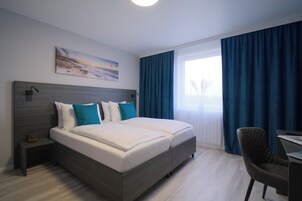 Ein modernes Hotelzimmer mit einem großen Bett, einem Schreibtisch und einem Stuhl.
