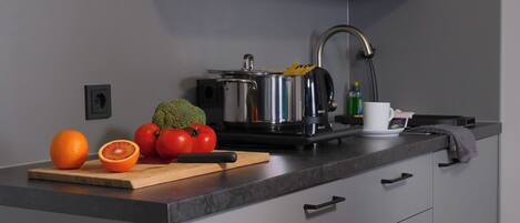 Uma cozinha moderna com uma panela de aço inoxidável, uma tábua de corte com legumes e uma pia.