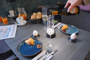 Een ontbijtsetting met croissants, een glas witte wijn en een fles Prosecco die wordt in geschonken.