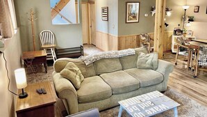 A cozy living room with a green sofa, a wooden coffee table, and a painting on the wall. - Spacious 4BR Escape in Sherwood Forest (Grayling)