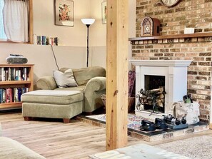 Un salon chaleureux avec une cheminée, une bibliothèque et une radio.