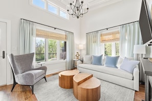 A modern living room with a grey armchair, a light-colored sofa, and two wooden side tables. - Afton Mountain Vineyards (Afton)