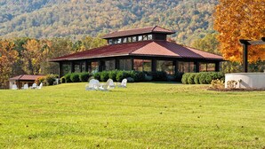 A large building with a covered patio area, surrounded by a grassy field and trees. - Afton Mountain Vineyards (Afton)