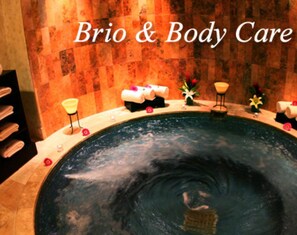 Wellnessbereich mit großzügigem Whirlpool, Handtüchern und Blumen.