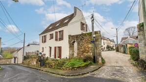 Ein traditionelles Steinhaus mit geneigtem Dach, einer Steinmauer und einem kleinen Garten.