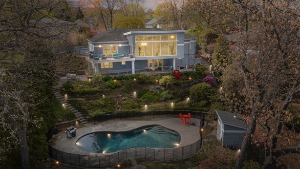 A modern house with a large pool, surrounded by a landscaped garden and a deck. - Majestic lakefront 3-bedroom with pool, hot tub, water sports and birdwatching (Arlington)