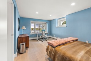 Un dormitorio con cama, escritorio, silla y ventana.