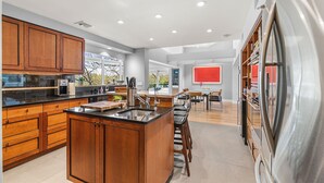 A modern kitchen with wooden cabinets, a central island, and a stainless steel refrigerator. - Majestic lakefront 3-bedroom with pool, hot tub, water sports and birdwatching (Arlington)
