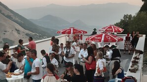 A terrace with people dining and socializing, outdoor seating, and a view of distant mountains. - tartufo hotel (Colliano)