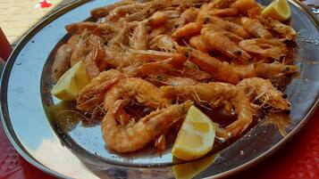 A plate of cooked shrimp with lemon wedges on a metal tray.