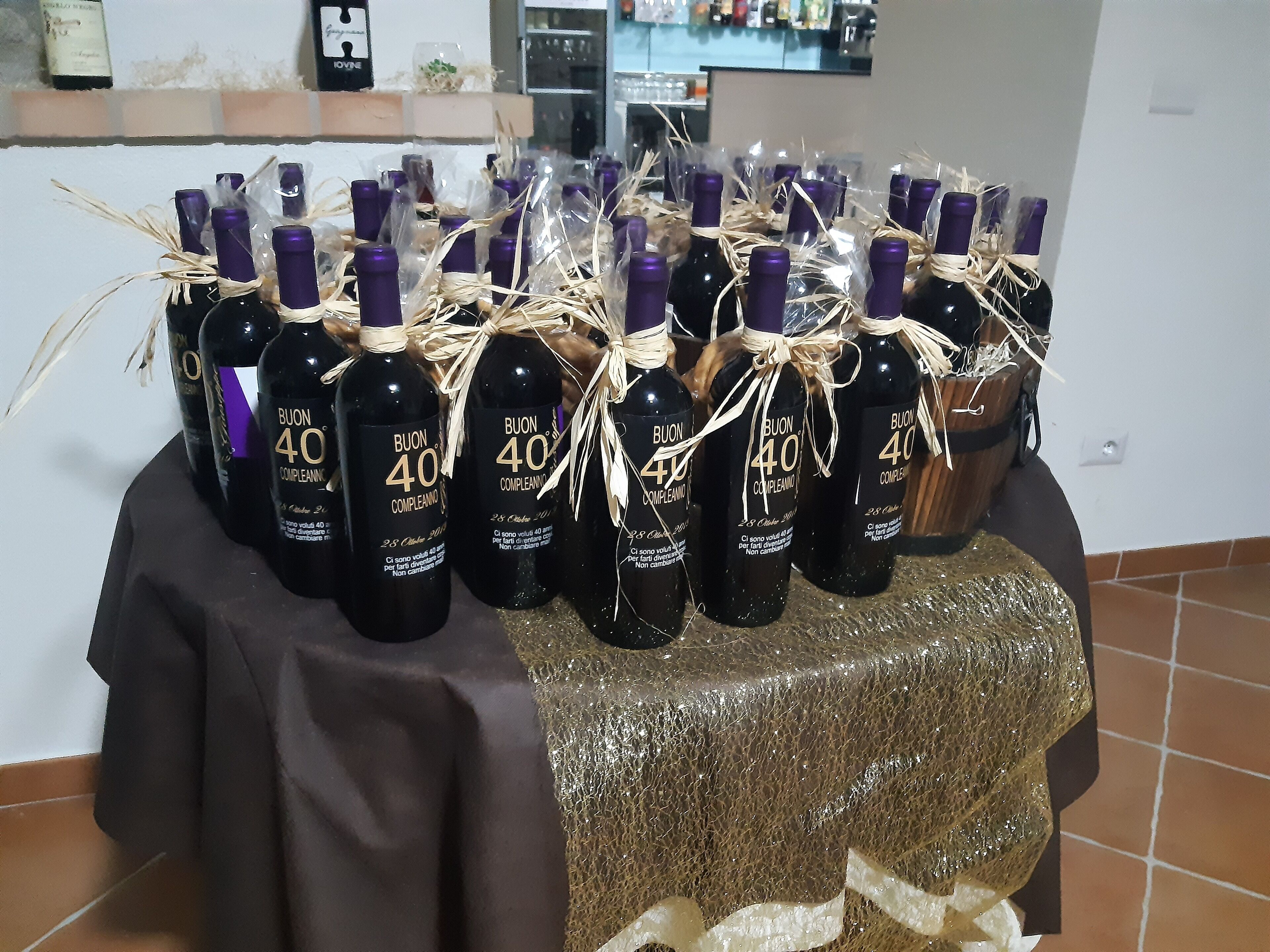 Una mesa con botellas de vino Buon 40, atadas con cuerda y paja, sobre un mantel.