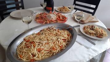 A dining table with various dishes, including pasta, bread, and a bottle of wine.