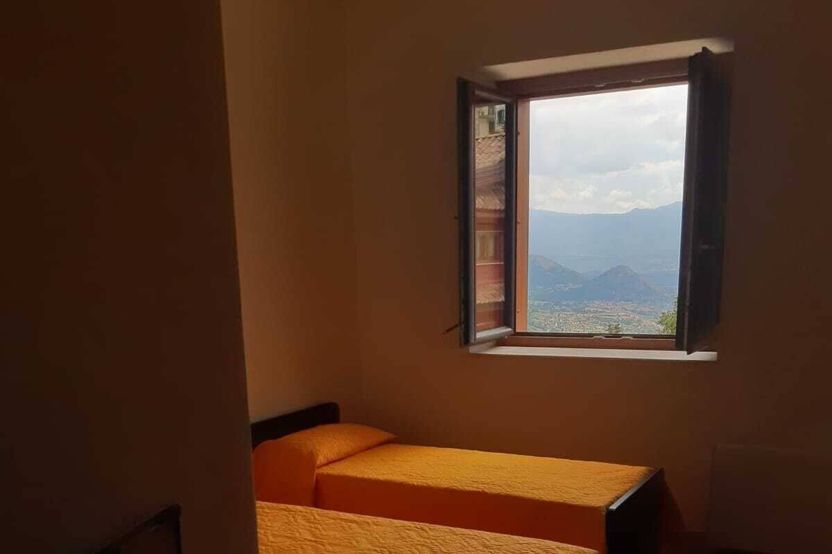 Une petite chambre avec deux lits, un bureau et une fenêtre donnant sur les montagnes.