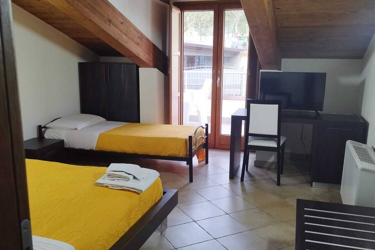 Une chambre avec deux lits, un bureau, une télévision et un appareil de climatisation.