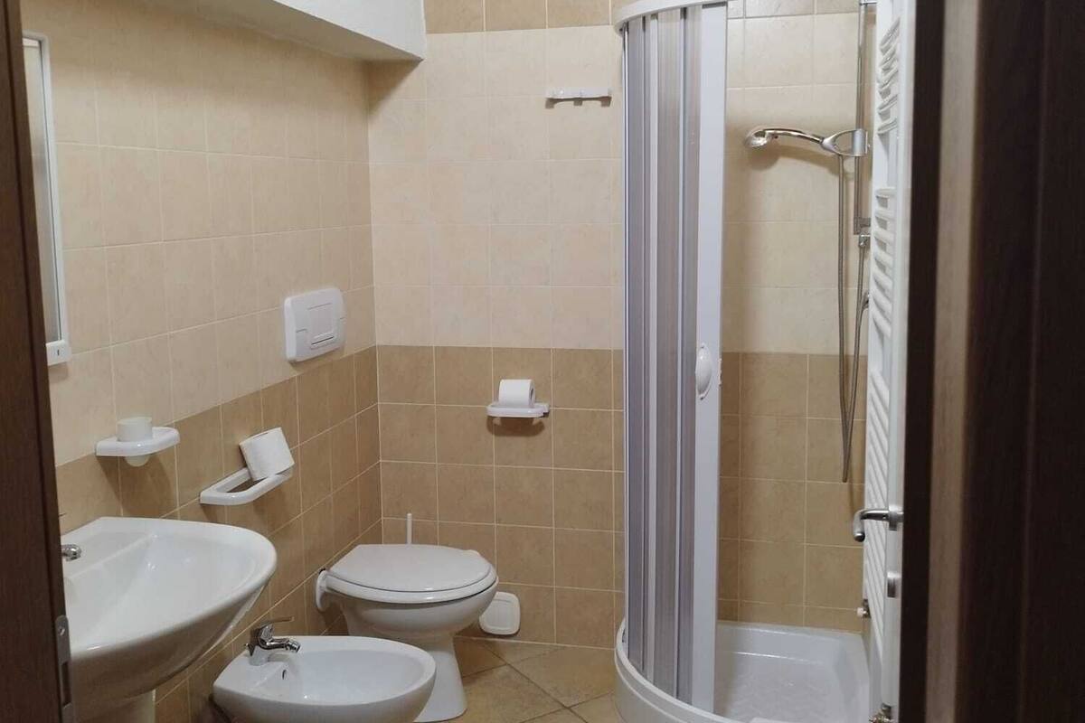 Une salle de bain comprenant des toilettes, un bidet, un lavabo et un espace douche.