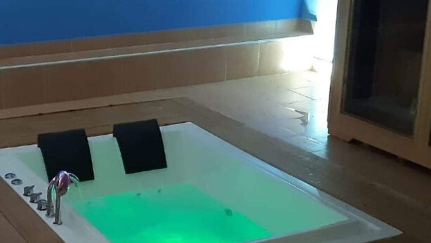 A room with a large bathtub, a wooden floor, and a blue wall. - tartufo hotel (Colliano)