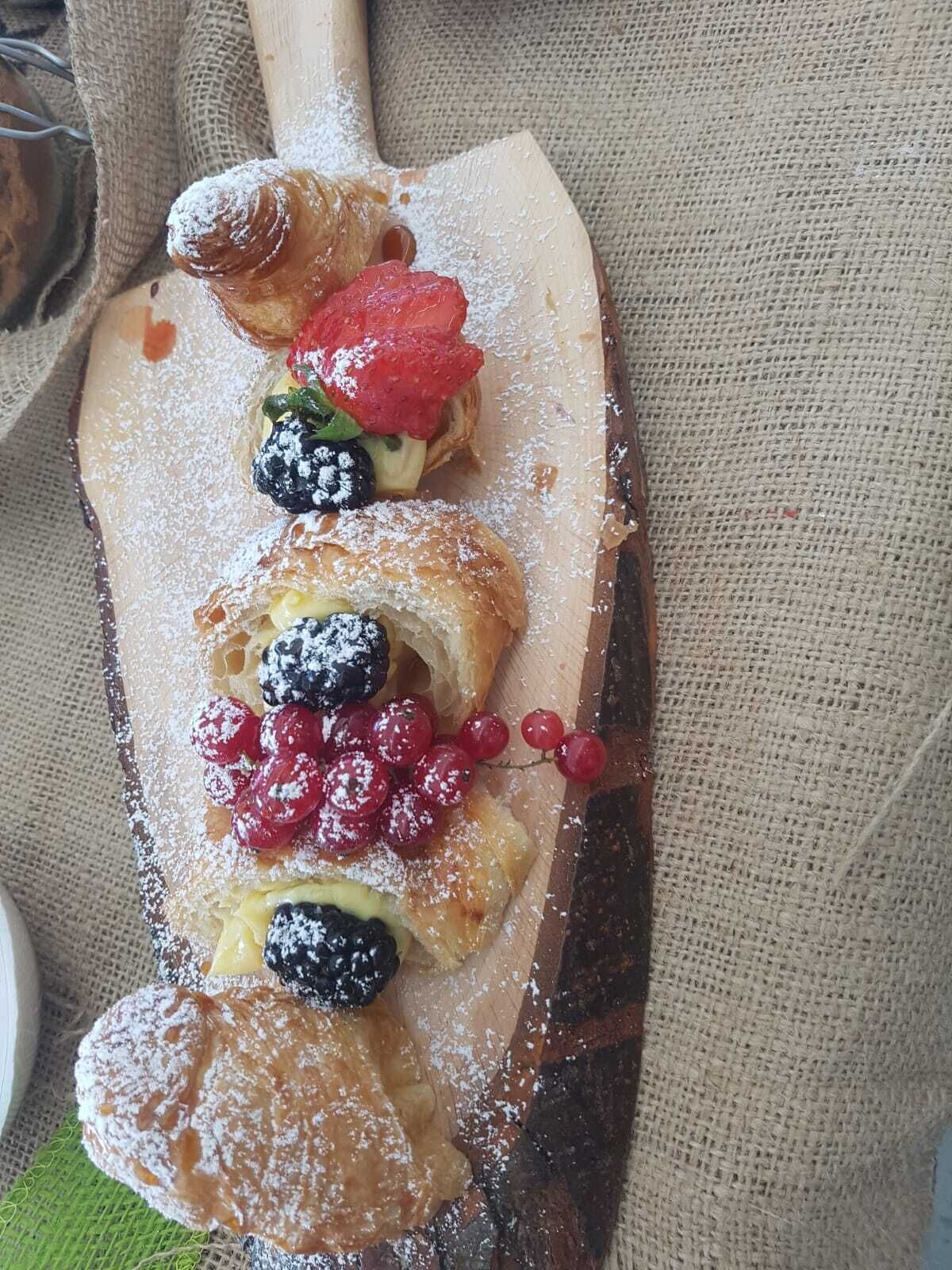 A wooden serving board with pastries and berries.