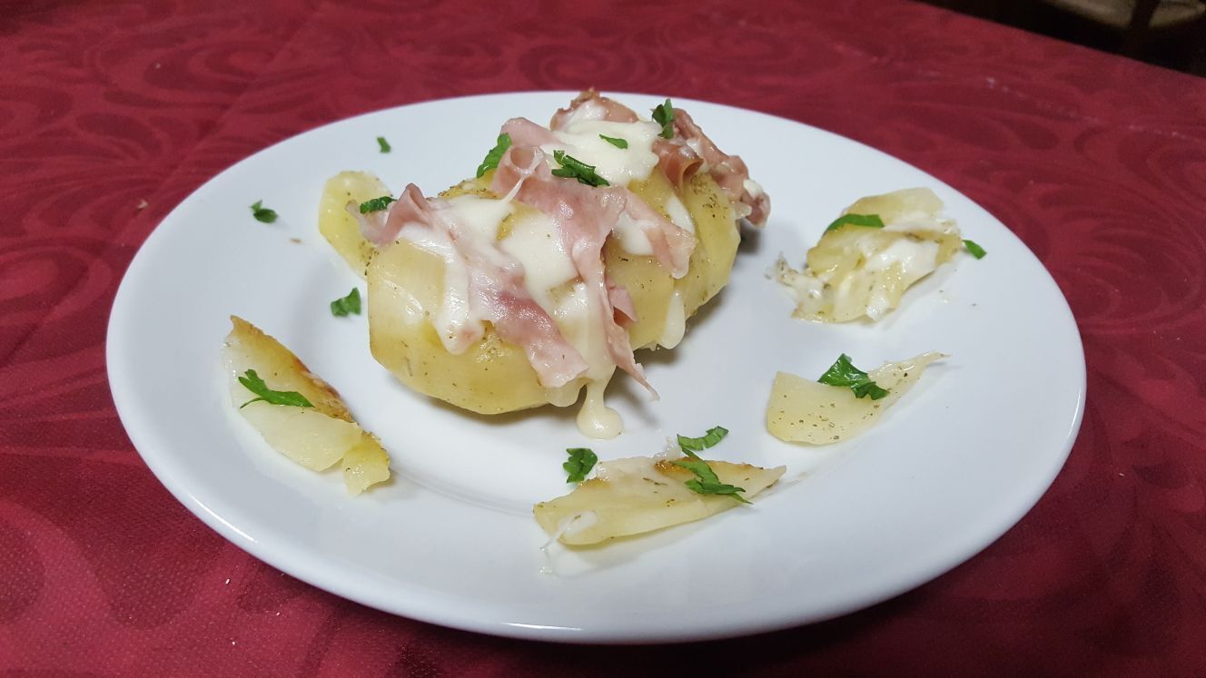 Ein Teller Essen mit Kartoffeln und Käse auf weißem Geschirr.