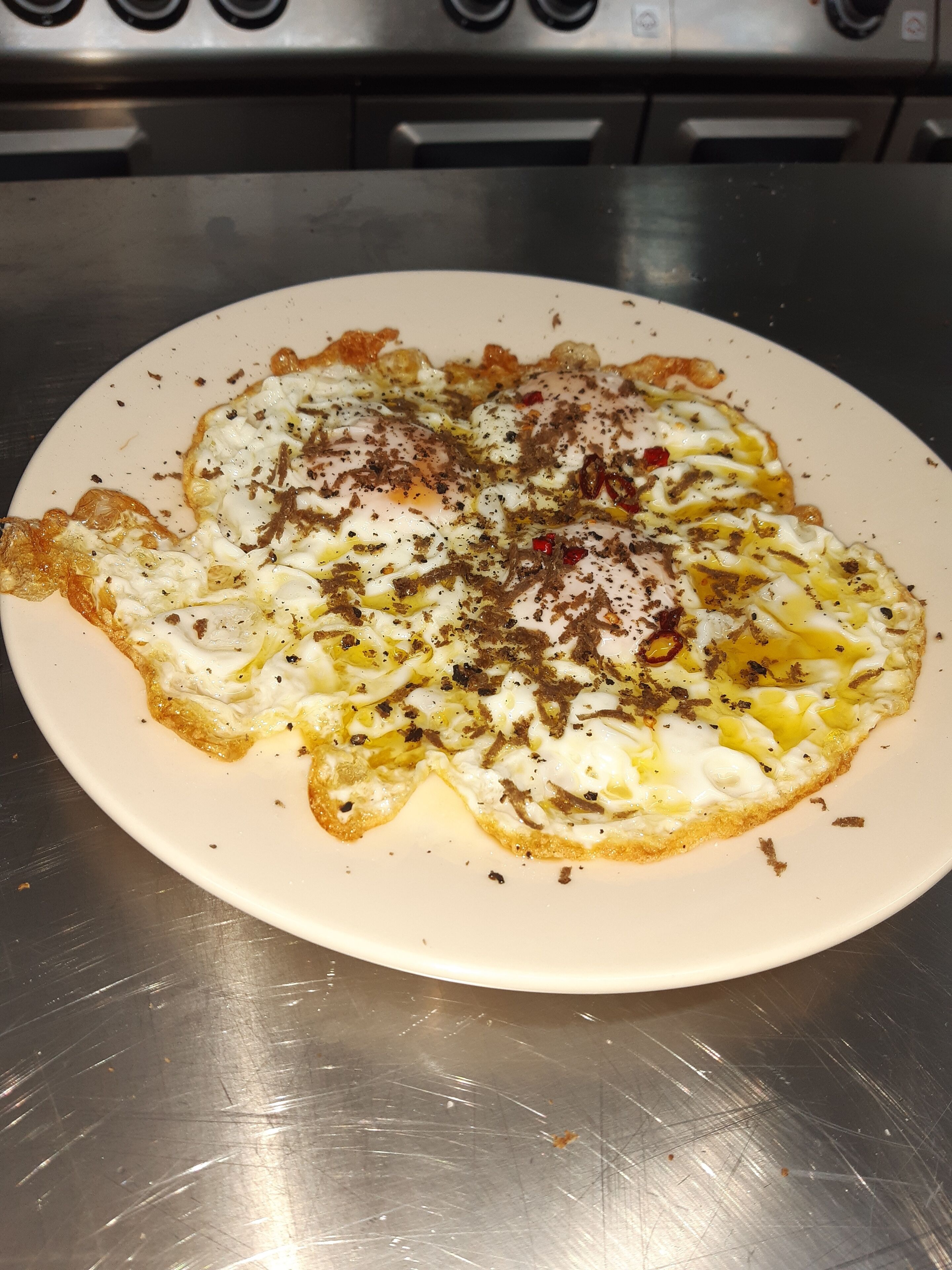 Un plato de comida con un huevo frito y acompañamientos sobre un plato blanco.