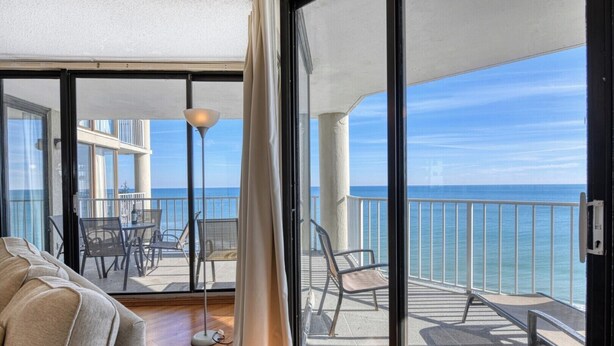 A balcony with a view of the sea, a sofa, and a floor lamp. - One Ocean Place 1105- Three Bedroom, Three Bath Oceanfront Condo (Garden City Beach)