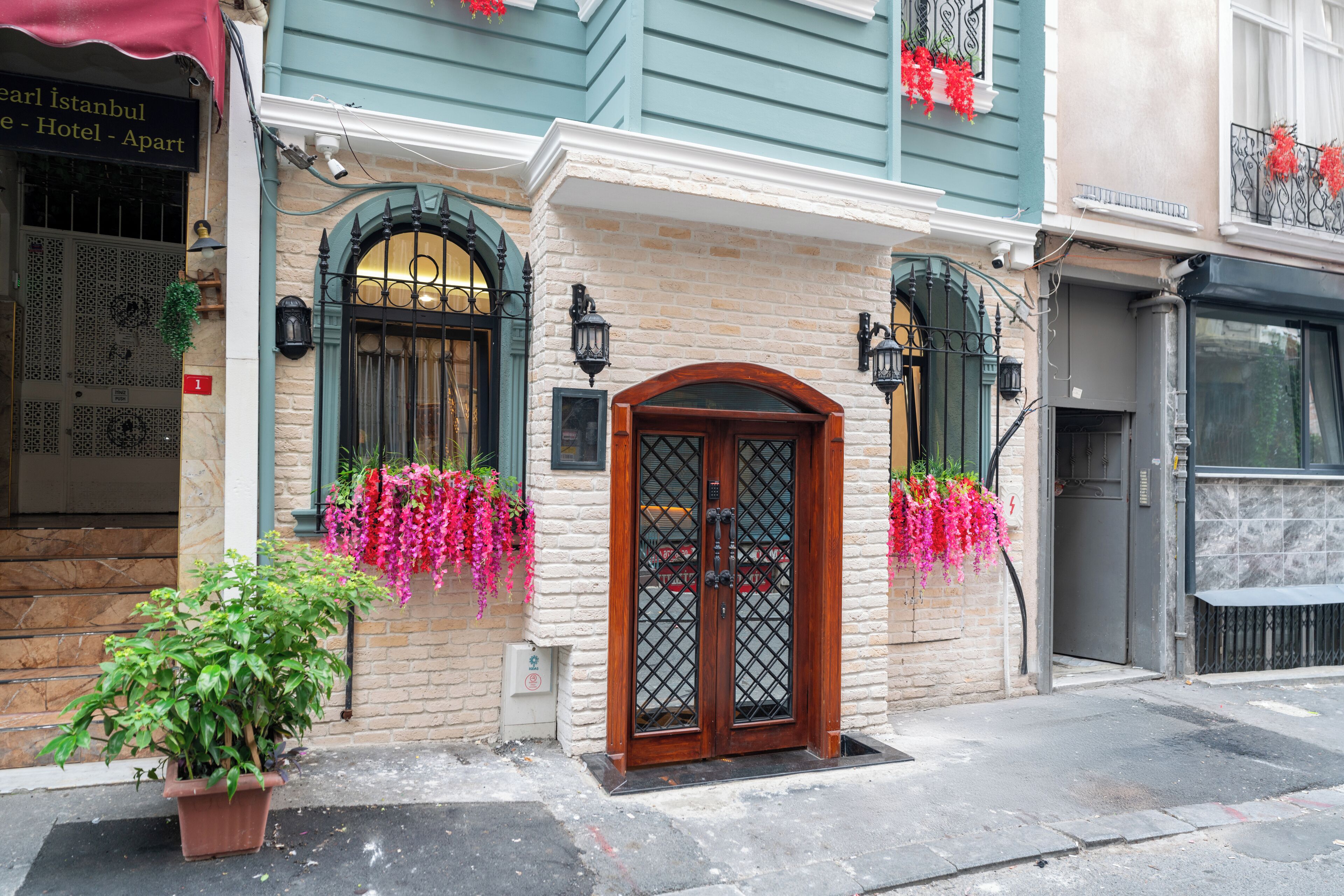 A hotel entrance with a wooden door, a brick facade, and hanging flower baskets.
