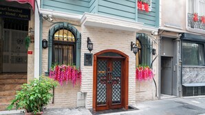 A hotel entrance with a wooden door, a brick facade, and hanging flower baskets. - The Mua Luxury Homes (Istanbul)
