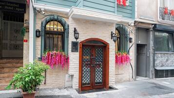 A hotel entrance with a wooden door, a brick facade, and hanging flower baskets.