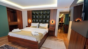 A modern bedroom with a large bed, wooden headboard, bedside tables with lamps, and a view into the dining area. - The Mua Luxury Homes (Istanbul)