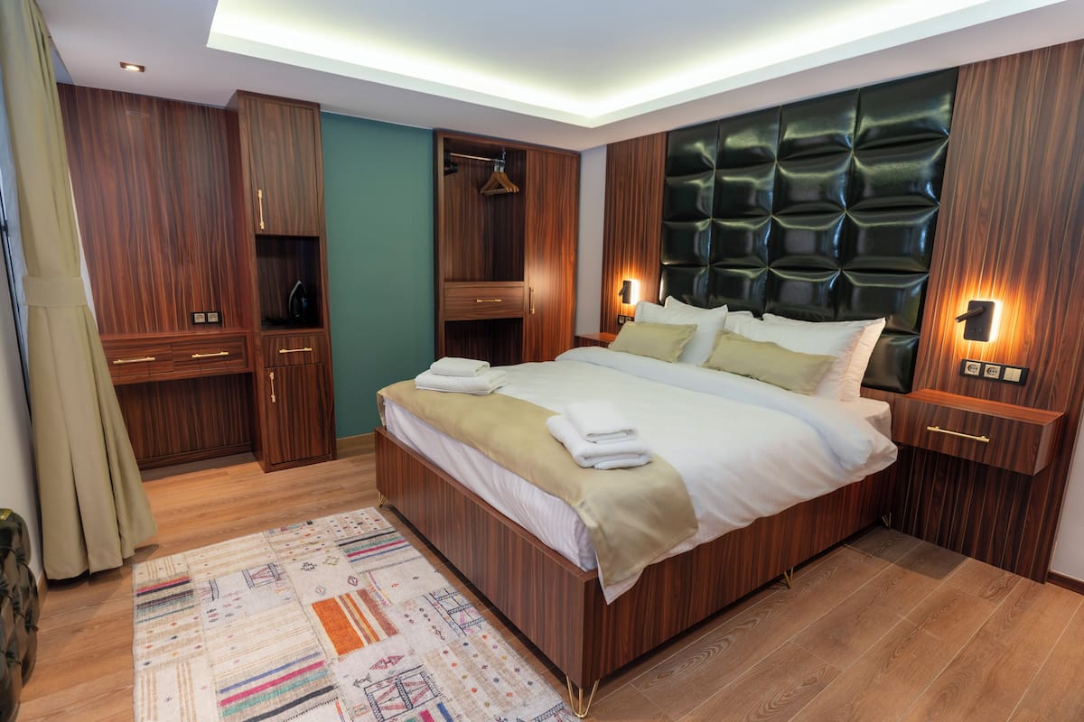 A modern bedroom with a large bed, wooden wardrobe, and built-in lighting.