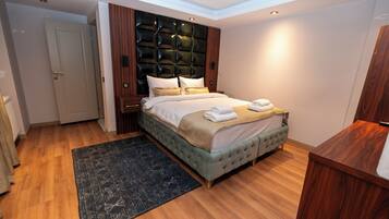 A modern bedroom with a tufted headboard, a large bed with a beige bedspread, and a dark patterned rug.