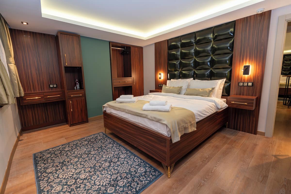 A modern bedroom with a large bed, wooden wardrobe, and built-in lighting.