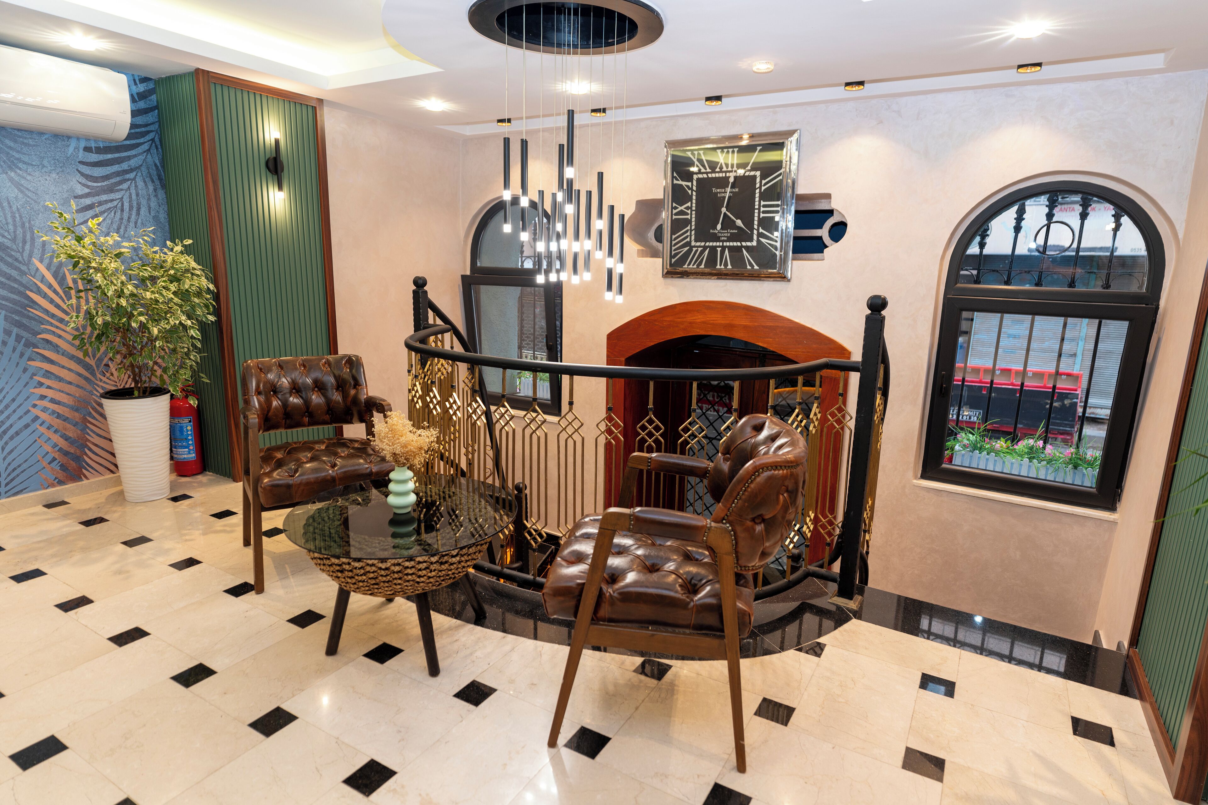 A lobby with a fireplace, leather chairs, a glass coffee table, and a large clock on the wall.