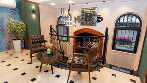 A lobby with a fireplace, leather chairs, a glass coffee table, and a large clock on the wall. - The Mua Luxury Homes (Istanbul)