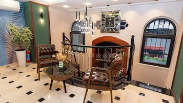 A lobby with a fireplace, leather chairs, a glass coffee table, and a large clock on the wall.